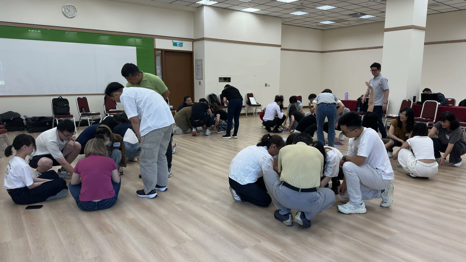 在室內課程空間,參與者分成數組,圍坐地板進行共同任務。